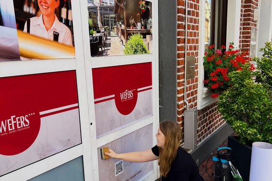 Lilly Vedler bei der Arbeit mit einem Schild an einer Fensterfront